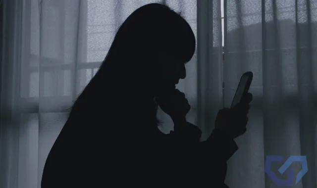 暗闇でスマホを眺める女性